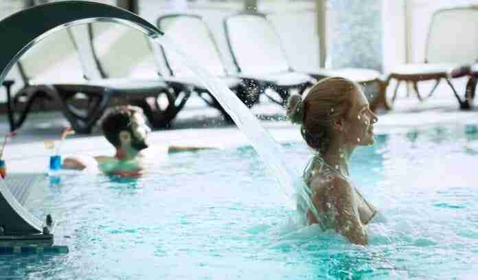 Woman enjoying hydrotherapy and water stream in spa pool