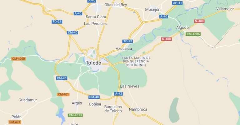 Bomberos trabajan para acceder a un turismo que ha quedado debajo de un camión tras chocar contra él en Toledo
