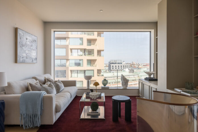 Sofá crema sobre alfombra burdeos en apartamento escandinavo contemporáneo