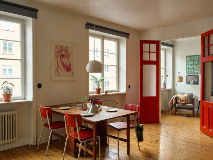 Comedor con sillas rojas vintage y puertas dobles lacadas en rojo en piso escandinavo - rojo vintage
