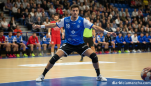 A handball player in action during an indoor match, defensive stance, stadium with spectators in background, realistic spo...