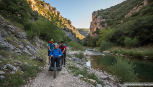A volunteer carefully guiding a Joelette (single-wheel mountain wheelchair) along a rocky trail through a scenic river gor...