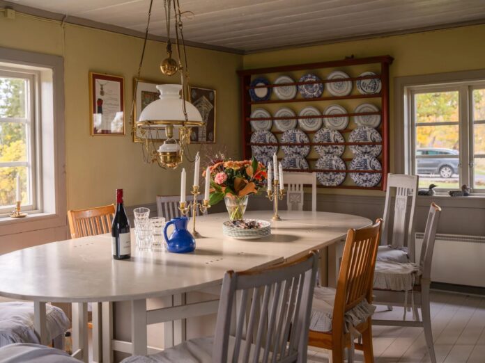 Comedor con mesa gustaviana, vajilla azul y blanca y expositor de platos en casa de campo sueca decoracion rústica