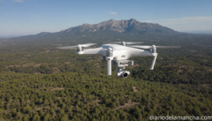 Dron compacto blanco volando sobre paisaje verde con montañas al fondo