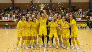 Young female futsal players in yellow jerseys celebrating a national championship title on an indoor court, joyful team mo...