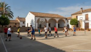 Outdoor summer basketball camp scene at a municipal court in a small Spanish village, children and teenagers in sports clo...