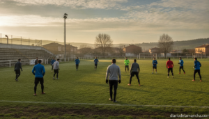 Photojournalistic wide shot of amateur football players training on a grass pitch at a small town stadium during preseason...